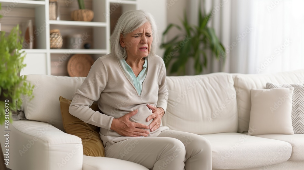 Older woman sitting on the sofa with stomach pain Older woman sitting on the sofa with stomach pain