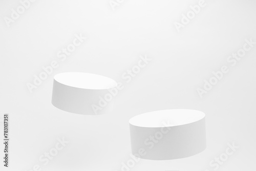 Set of two round tilt white podiums for cosmetic products mockup, soar on white background. Stage for presentation skin care products, gifts, goods, advertising, design, sale in contemporary style.
