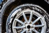 Man washing car's alloy wheels with high pressure washing.