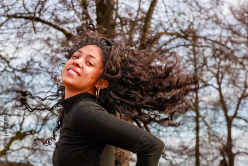 Model shoot in a park of a charming Latina girl tossing her curly hair