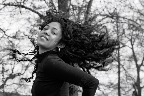 Model shoot in a park of a charming Latina girl tossing her curly hair