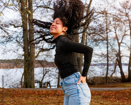 Model shoot in a park of a charming Latina girl tossing her curly hair