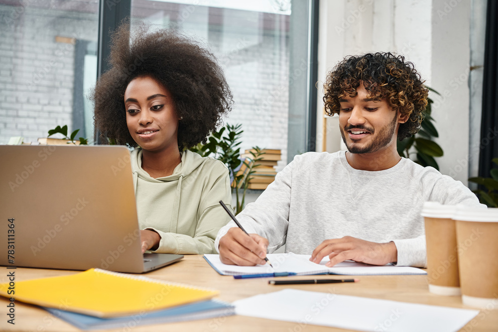 Multicultural students engage in collaborative studying with laptops in a modern coworking space. Multicultural students engage in collaborative studying with laptops in a modern coworking space.