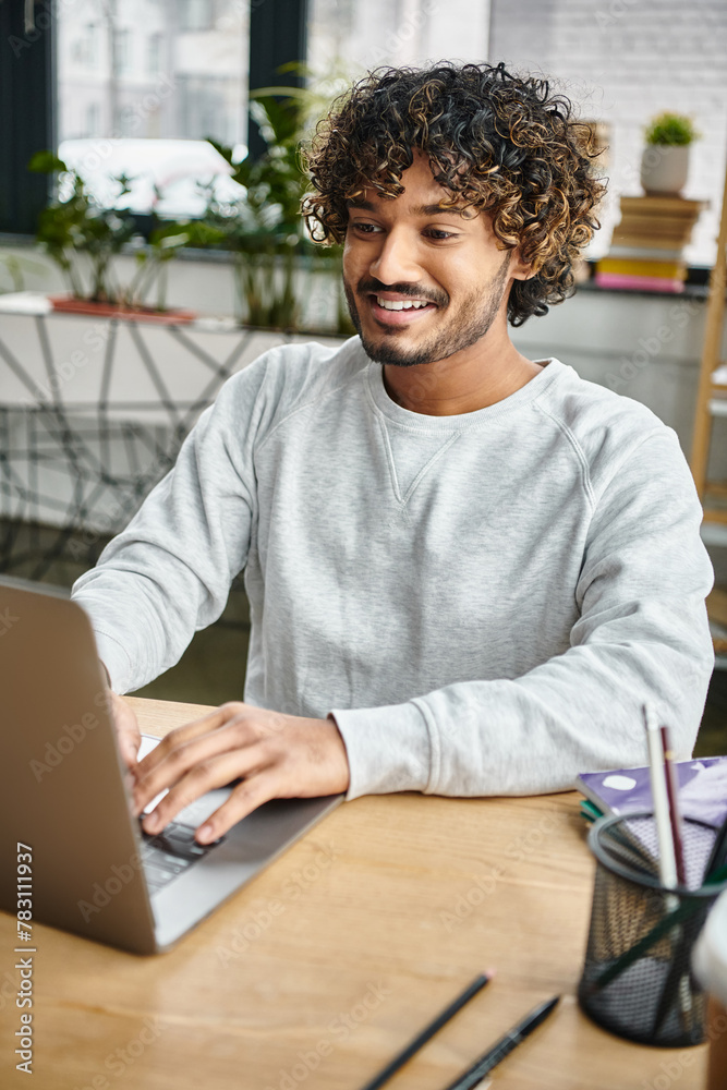 A man from a diverse group sits at a table, absorbed in his laptop screen in a modern coworking space. A man from a diverse group sits at a table, absorbed in his laptop screen in a modern coworking space.