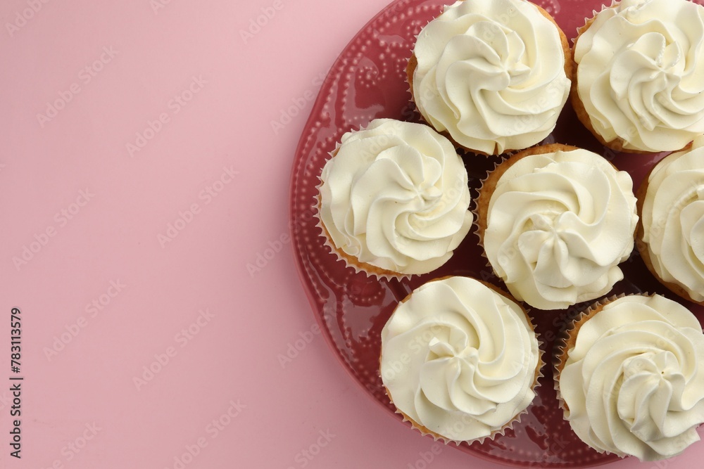 Tasty vanilla cupcakes with cream on pink background, top view. Space for text
