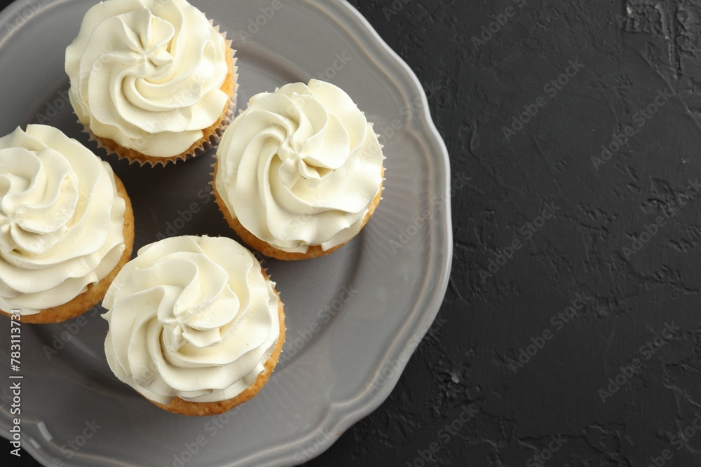 Tasty cupcakes with vanilla cream on black table, top view. Space for text Tasty cupcakes with vanilla cream on black table, top view. Space for text