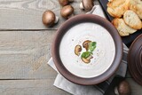 Delicious homemade mushroom soup in ceramic pot and fresh ingredients on wooden table. Space for text