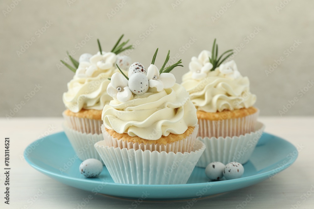 Tasty Easter cupcakes with vanilla cream on light wooden table, closeup