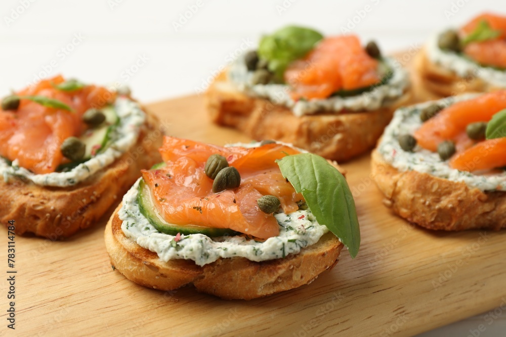 Tasty canapes with salmon, capers, cucumber and sauce on table, closeup Tasty canapes with salmon, capers, cucumber and sauce on table, closeup