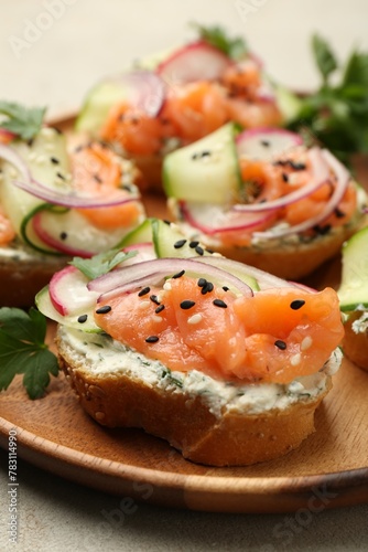Tasty canapes with salmon served on light grey table, closeup