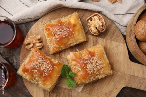 Eastern sweets. Pieces of tasty baklava and tea on wooden table, flat lay