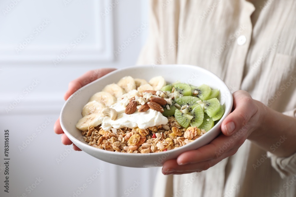 Woman holding bowl of tasty granola indoors, closeup Woman holding bowl of tasty granola indoors, closeup
