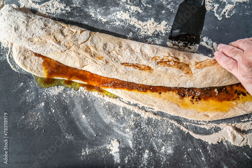 Teig wird in der Küche mit geschmolzener Butter und Zimt bestrichen photo