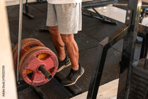 Foto Dedicated anonymous man at the gym setting does calf raises on a weight-loaded machine with plates, focusing on lower body strength