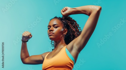 A determined young woman with defined muscles flexing her biceps against a vibrant blue backdrop