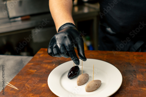 фотографія close-up in a professional kitchen chef in black gloves takes a delicacy for gla