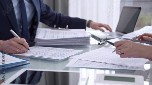 Business colleagues accountants or auditors reviewing financial data in office. Two professionals analyzing paper reports and using calculators. Audit and taxes