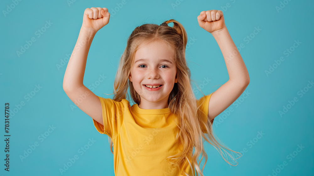 Fototapeta premium Portrait of a happy young blonde girl celebrating success on pastel blue background
