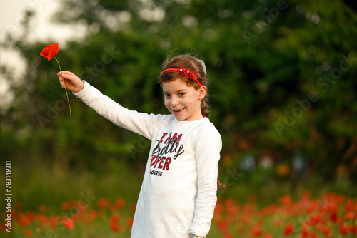 Bambina con capelli rossi che offre un papavero, immersa nella natura