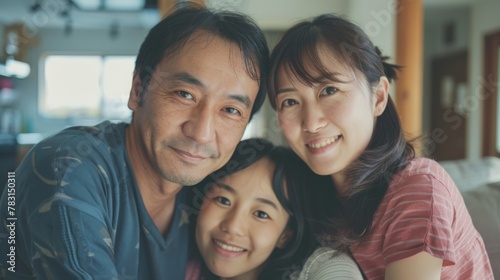 A man and two women are standing together, posing for a family portrait photograph. They are smiling and looking at the camera, with a background that is not clearly visible.
