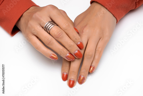 Orange manicure with glitter on oval short nails close-up on a white background. Cyprus nail color.