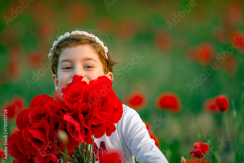 Bambina bella nascosta tra i papaveri che sorride in una giornata di sole photo