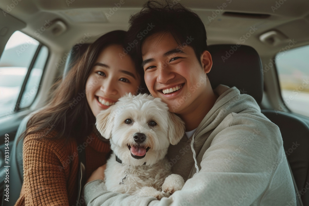 Young couple sitting in the back seat of a car with a dog in the front seat on a road trip vacation