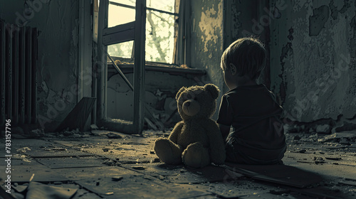 Young boy and his teddy bear are sitting on the floor of a dark