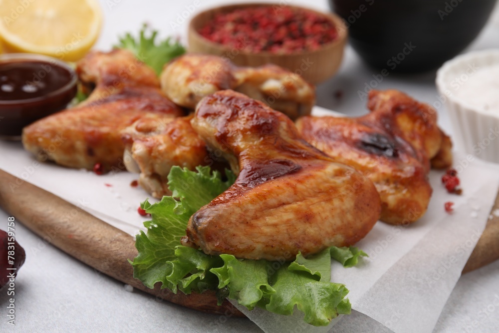 Fresh marinated chicken wings and lettuce on light table, closeup