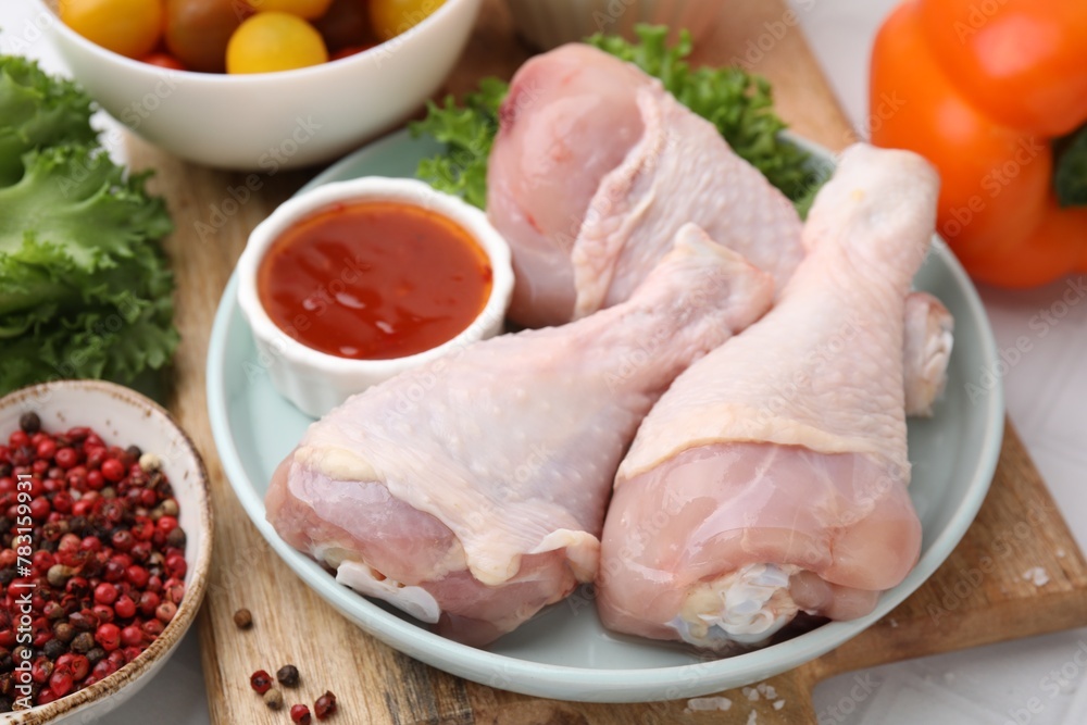 Fresh marinade, raw chicken drumsticks and other products on table, closeup