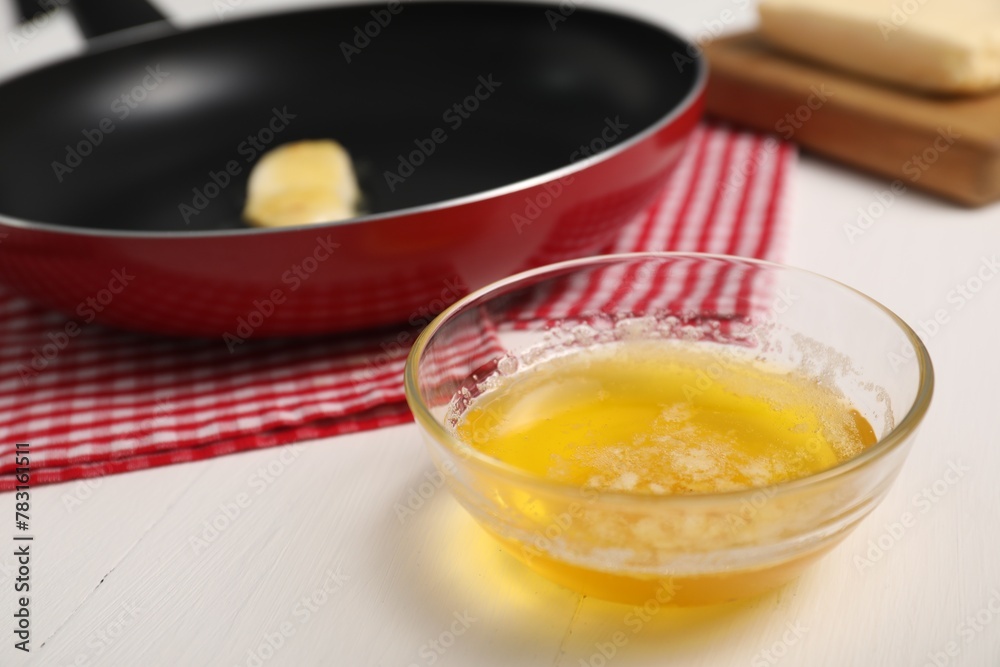 Melted butter in glass bowl on white wooden table, closeup Melted butter in glass bowl on white wooden table, closeup