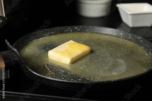 Melting butter in frying pan on black table, closeup