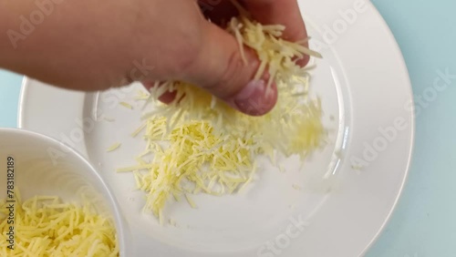 gros plan sur la main d'une personne remplissant une assiette de fromage râpé photo