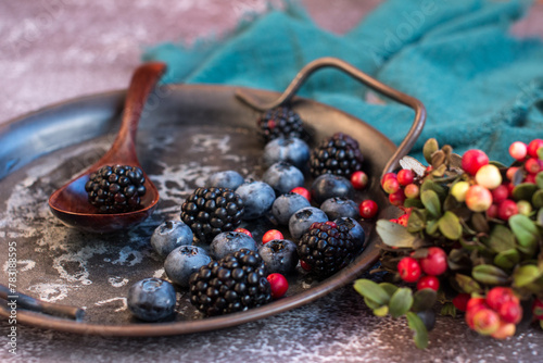 Blackberries and blueberries on a metal platter. Summer harvest of cranberries