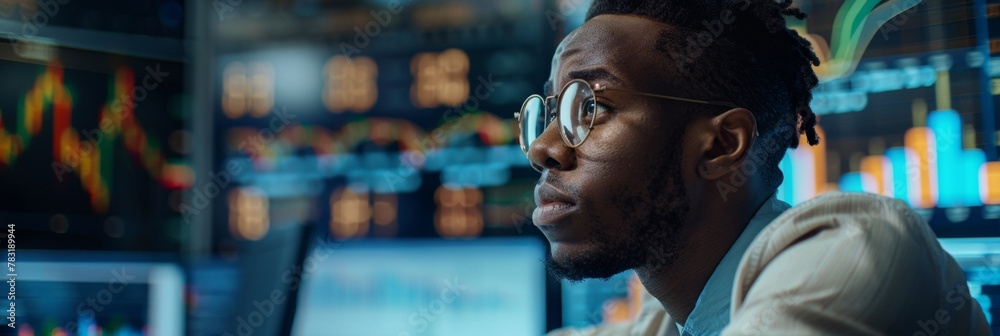 Young African-American Male Trader Focused on Financial Analysis in Office At Night Young African-American Male Trader Focused on Financial Analysis in Office At Night