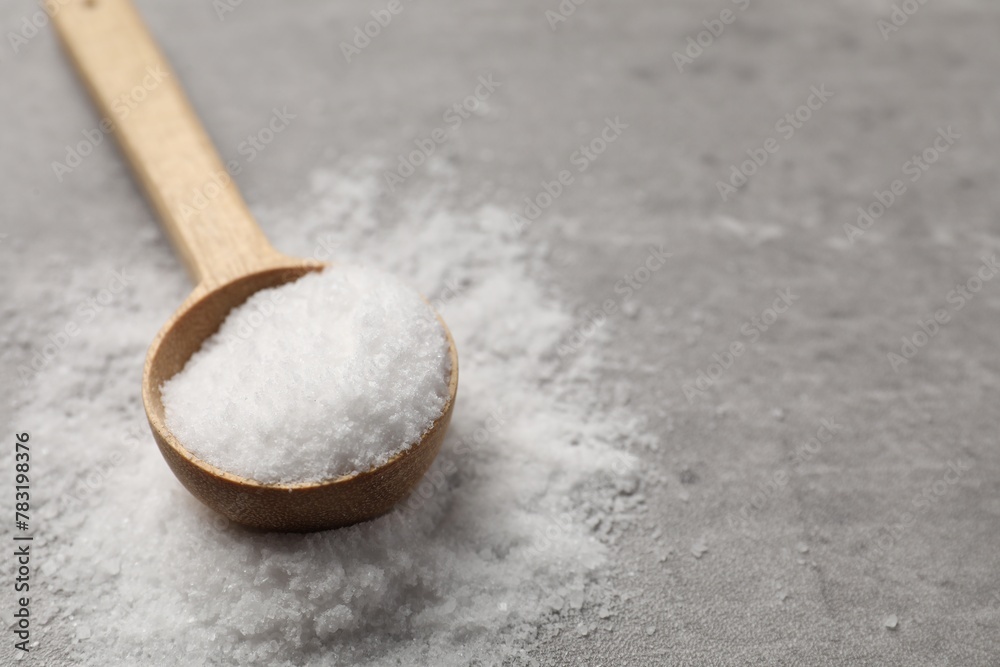 Natural salt and wooden spoon on grey table, closeup. Space for text Natural salt and wooden spoon on grey table, closeup. Space for text