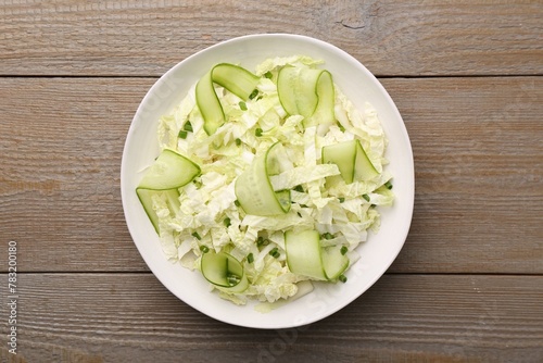 Tasty salad with Chinese cabbage, cucumber and green onion in bowl on wooden table, top view