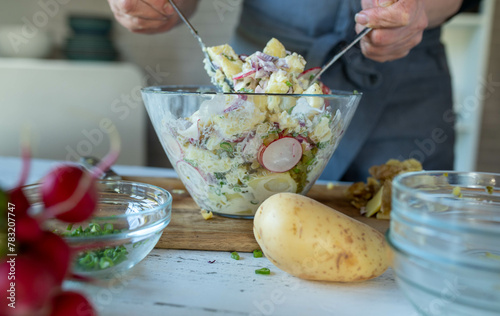 Making potato salad. Mixing ingredients in a salad bowl by womans hands