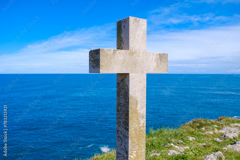 A Christian cross stands prominently on a hill, overlooking the vast expanse of the ocean. The cross is silhouetted against the horizon, with waves crashing in the distance. A Christian cross stands prominently on a hill, overlooking the vast expanse of the ocean. The cross is silhouetted against the horizon, with waves crashing in the distance.