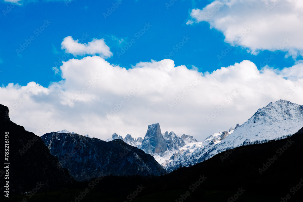 A view of the towering Pico Urriellu, also known as El Naranjo, in the Asturian mountain range, with clouds covering the sky.