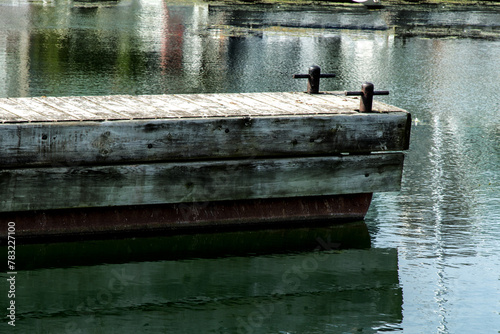 A marina floating dock with two mooring cleats in still water with reflections of boats photo