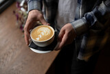Person's hands Holding a Freshly Made Cappuccino With Artful Foam Design