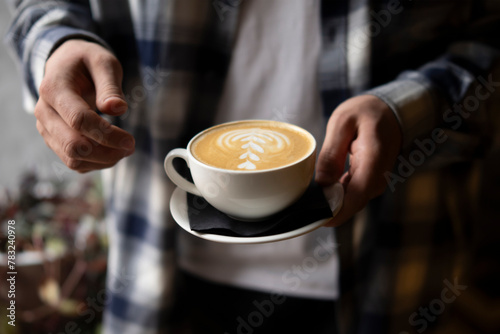Person s hands Holding a Freshly Made Cappuccino With Artful Foam Design