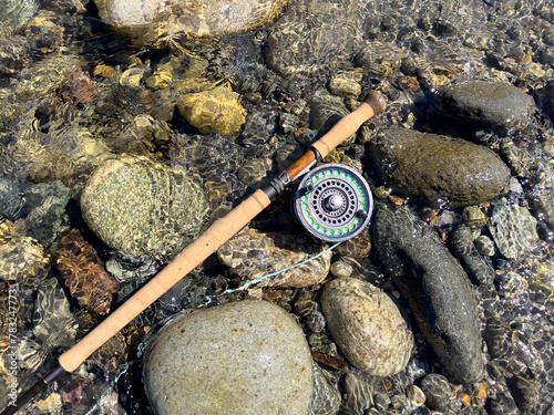 Fly fishing rod and reel on flowing river bed