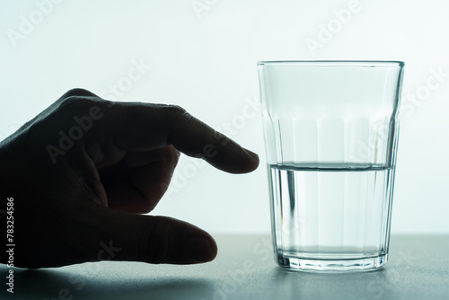 A glass half full of water concept, with a hand showing the part of a half of water, positive mindset, and point of view.