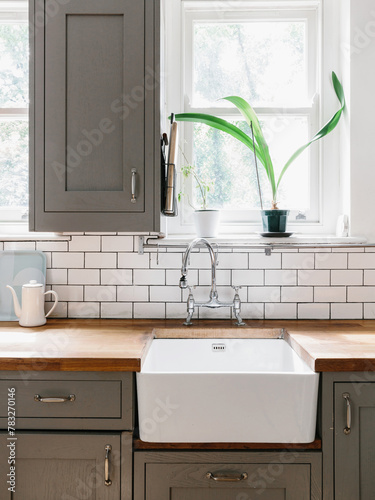 Portrait of a clean and classic kitchen sink with cupboards. 