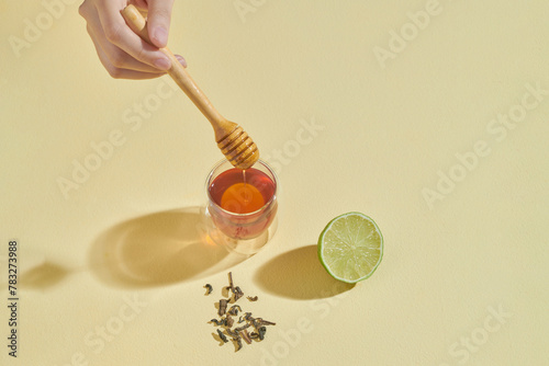 Honey lime drink on light yellow table with fresh lime and honey.