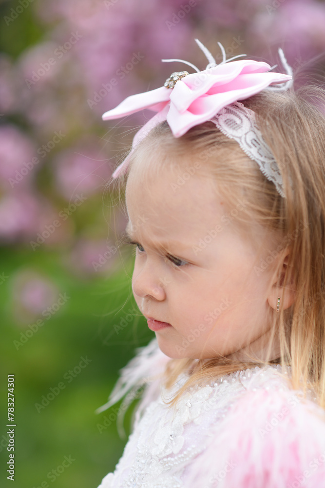 Fototapeta premium little girl in pink dress. little girl with pink flowers. little girl walking in the park
