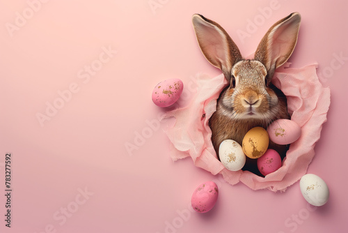 Easter Bunny with chocolate easter eggs on pastel wall background.