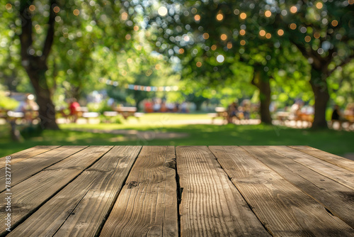 Empty wooden table in summer background with the blurred green garden and party in the background. photo